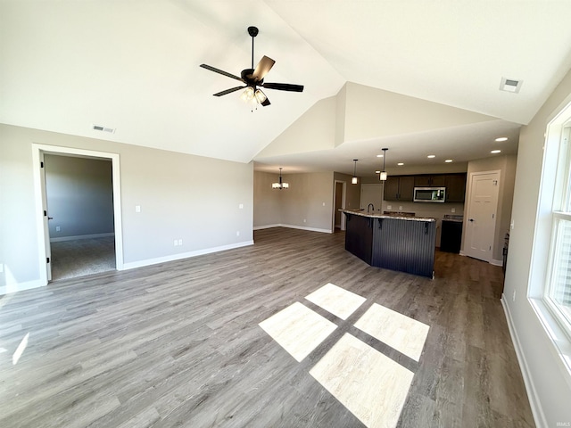 2360 Serenity Ct, Auburn, IN 46706 - unfurnished living room with ceiling fan, high vaulted ceiling, light wood-type flooring, baseboards, and a chandelier