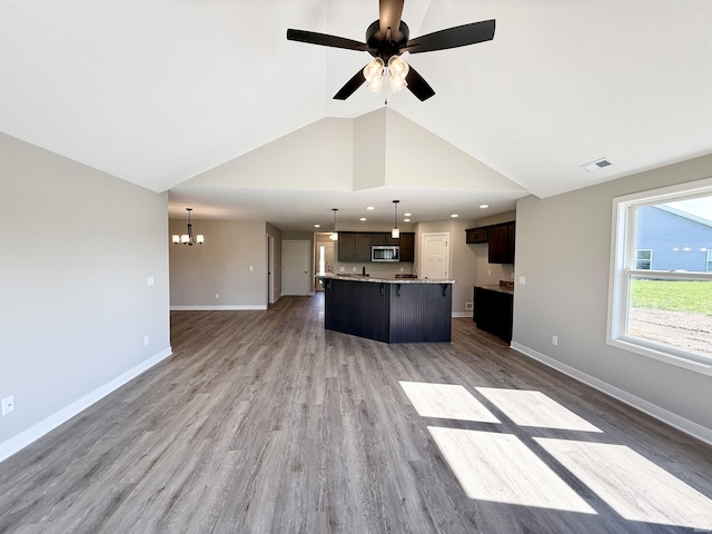 2360 Serenity Ct, Auburn, IN 46706 - unfurnished living room with a chandelier, baseboards, a ceiling fan, vaulted ceiling, and wood finished floors