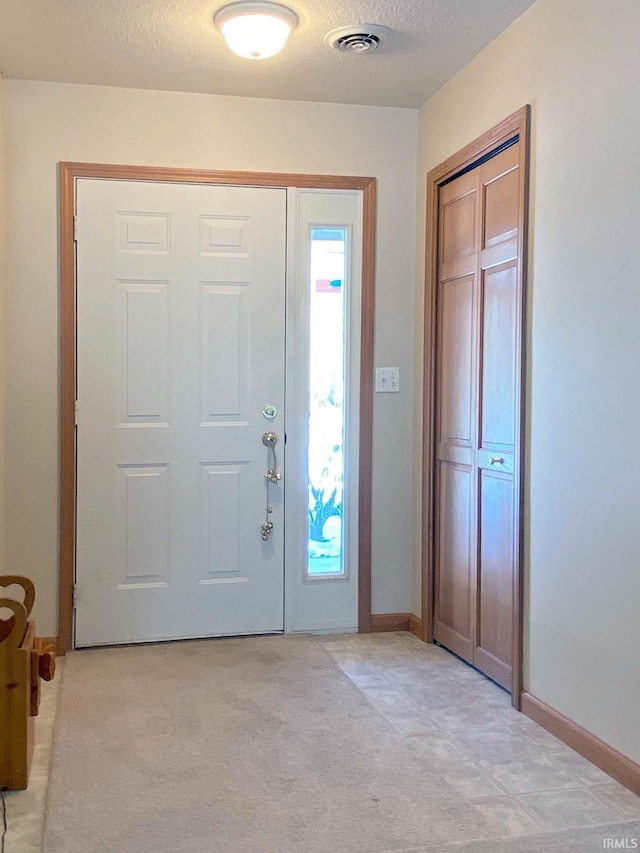 entryway with light carpet and a textured ceiling