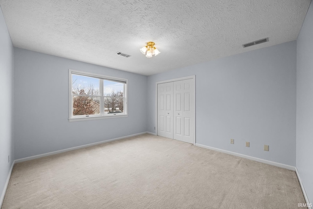 unfurnished bedroom with light colored carpet, a closet, and a textured ceiling