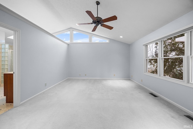 spare room featuring vaulted ceiling, light carpet, a wealth of natural light, and ceiling fan