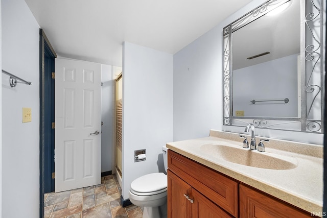 bathroom featuring vanity, toilet, and a shower with door