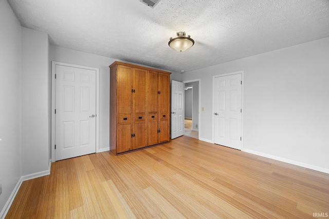 unfurnished bedroom with light hardwood / wood-style floors and a textured ceiling