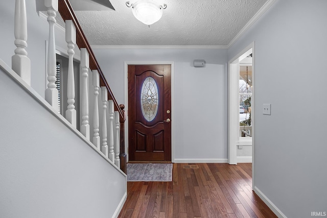 foyer entrance featuring dark wood-type flooring, ornamental molding, and a textured ceiling