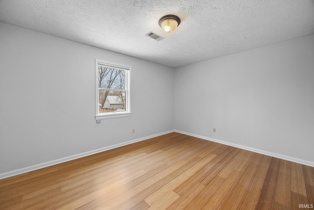 unfurnished room with a textured ceiling and light hardwood / wood-style flooring