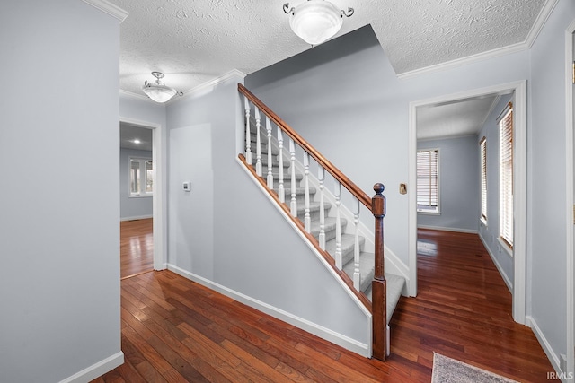 staircase featuring hardwood / wood-style floors, ornamental molding, and a textured ceiling