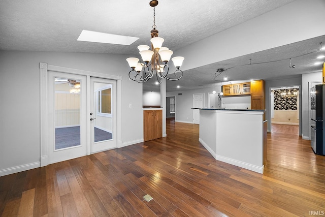 kitchen featuring decorative light fixtures, dark hardwood / wood-style flooring, vaulted ceiling with skylight, and a textured ceiling