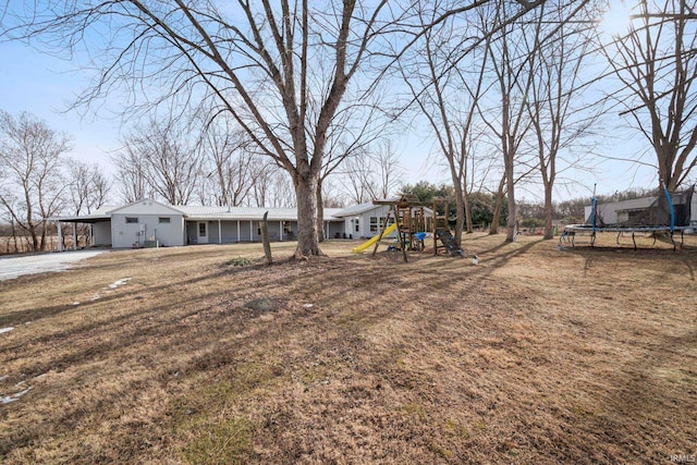 view of yard with a playground, a carport, and a trampoline