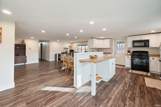 kitchen with white cabinetry, a center island, a textured ceiling, a kitchen breakfast bar, and black appliances