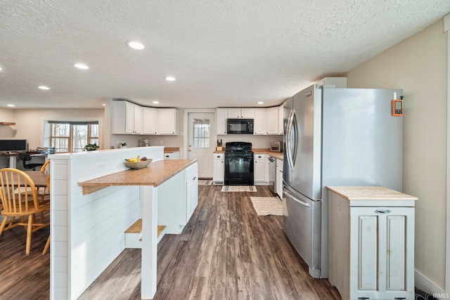 kitchen featuring a kitchen bar, black appliances, a textured ceiling, dark hardwood / wood-style flooring, and white cabinets