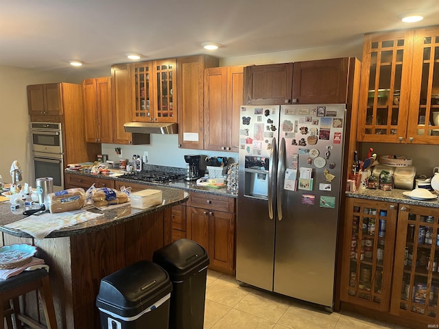 kitchen featuring dark stone countertops, light tile patterned floors, a breakfast bar, and appliances with stainless steel finishes