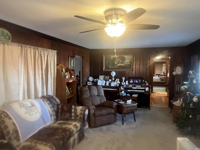 carpeted living room featuring ceiling fan and wooden walls