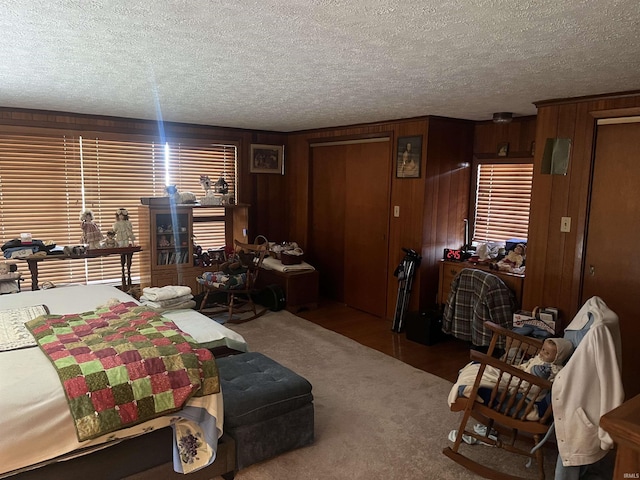 carpeted bedroom with a textured ceiling and wood walls