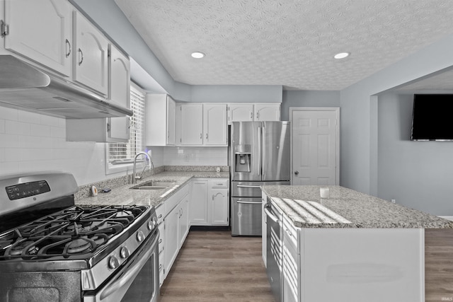 kitchen with sink, white cabinetry, light stone counters, a textured ceiling, and appliances with stainless steel finishes