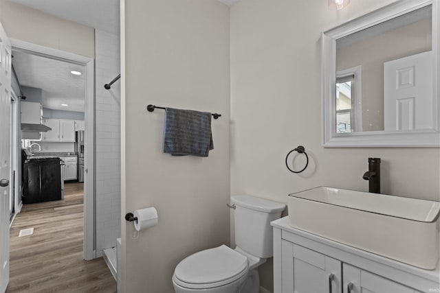 bathroom featuring walk in shower, wood-type flooring, toilet, and vanity