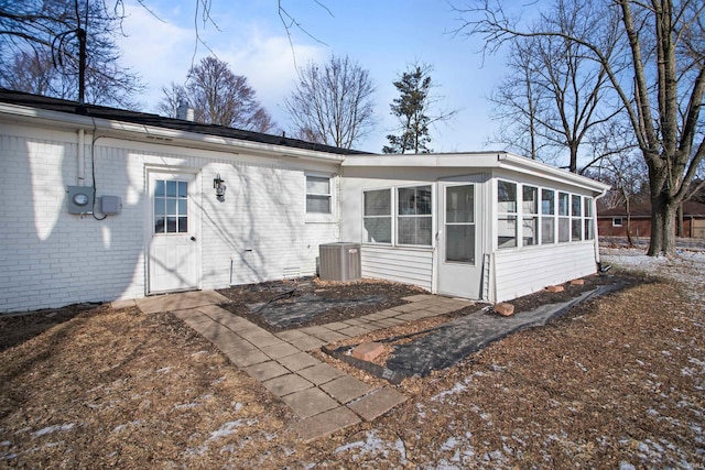 back of property with central AC unit and a sunroom