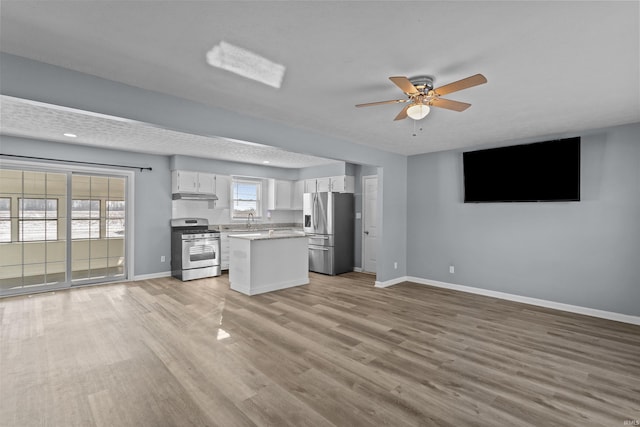 kitchen featuring a kitchen island, appliances with stainless steel finishes, white cabinetry, ceiling fan, and light hardwood / wood-style flooring