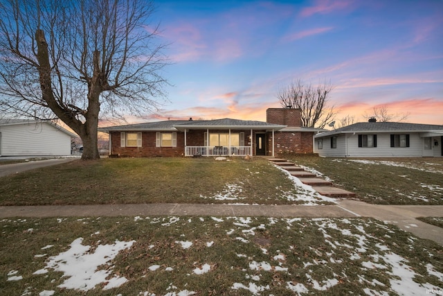 ranch-style home featuring a yard and covered porch