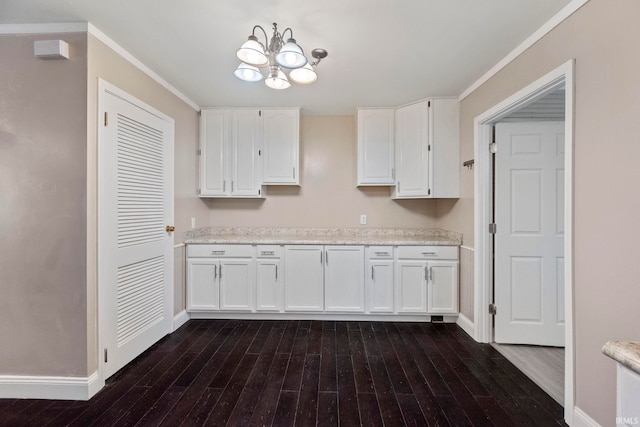 kitchen featuring white cabinetry, an inviting chandelier, ornamental molding, dark hardwood / wood-style floors, and light stone countertops