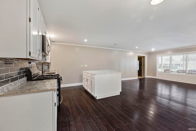 kitchen with appliances with stainless steel finishes, white cabinetry, backsplash, dark hardwood / wood-style flooring, and ornamental molding