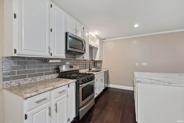 kitchen featuring appliances with stainless steel finishes, sink, white cabinets, ornamental molding, and dark wood-type flooring