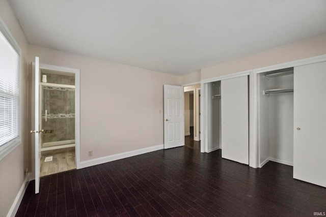 unfurnished bedroom with dark hardwood / wood-style floors, multiple closets, and ensuite bathroom