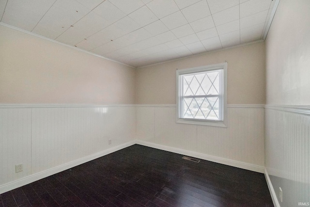 empty room featuring crown molding and wood-type flooring