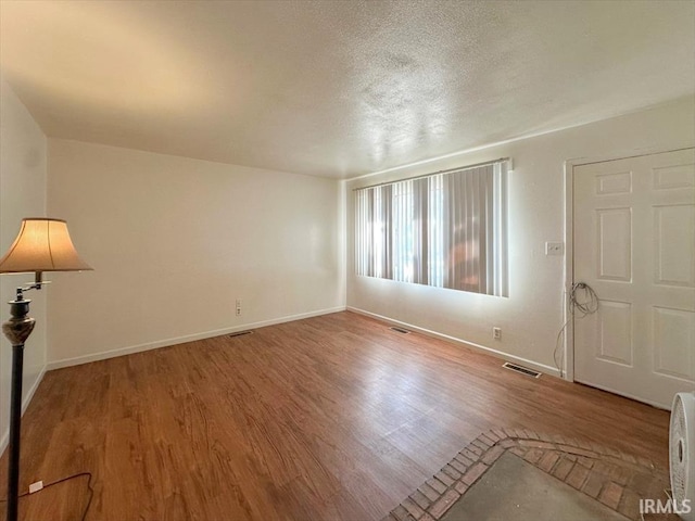 unfurnished room with wood-type flooring and a textured ceiling