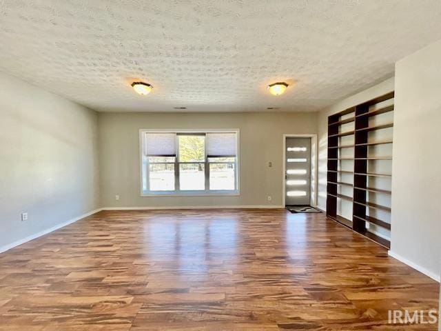 empty room with hardwood / wood-style floors and a textured ceiling