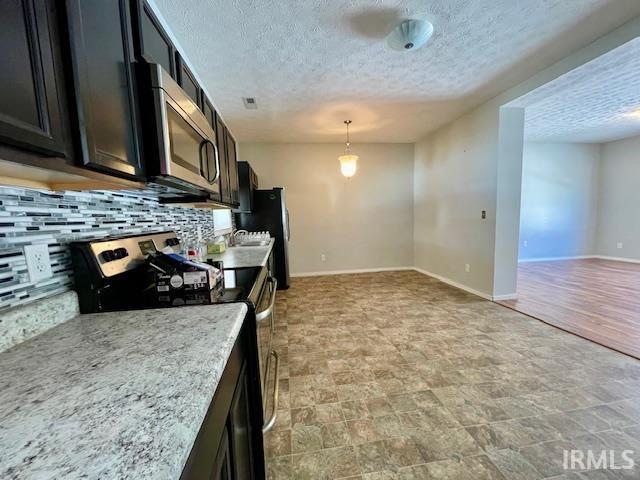 kitchen featuring stainless steel appliances, tasteful backsplash, pendant lighting, and a textured ceiling