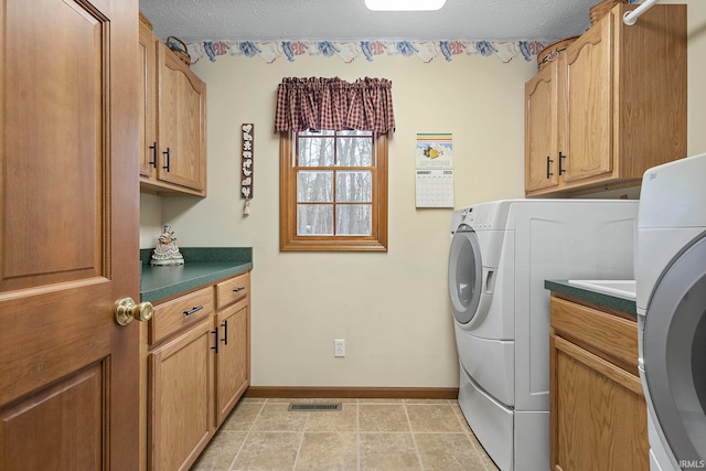 laundry room with washer and dryer, cabinets, and a textured ceiling