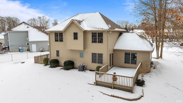 snow covered back of property featuring central AC unit