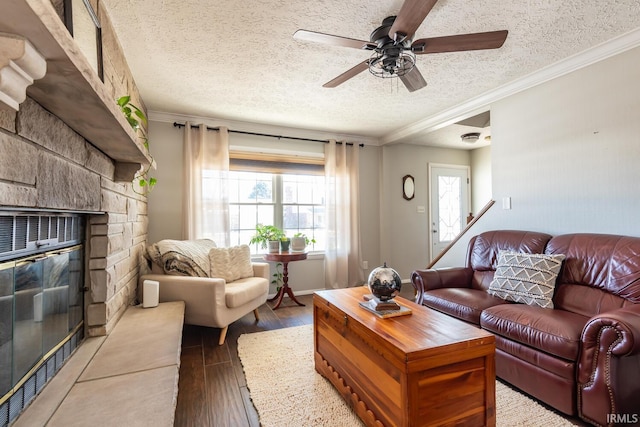 living room with a stone fireplace, wood-type flooring, ornamental molding, and a textured ceiling