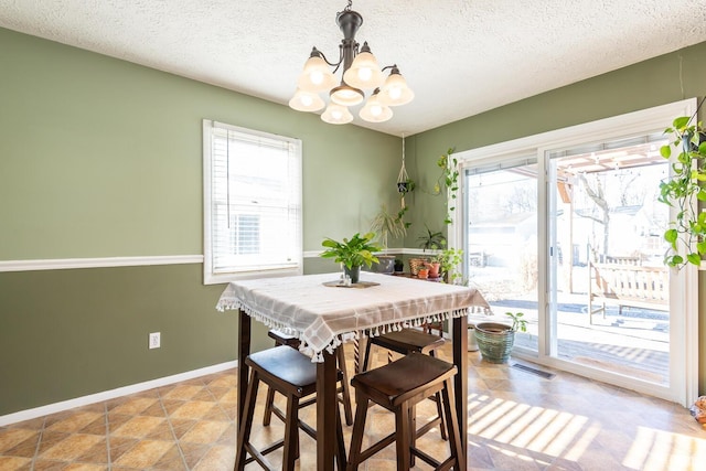 dining room featuring a healthy amount of sunlight, a textured ceiling, and a chandelier