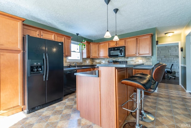 kitchen with pendant lighting, tasteful backsplash, a kitchen breakfast bar, a center island, and black appliances