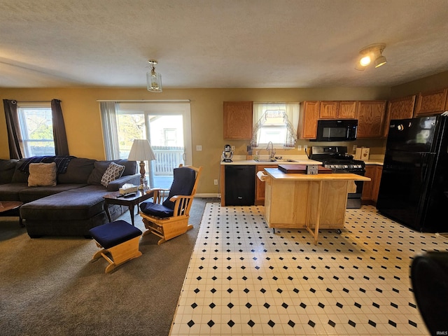 kitchen with a textured ceiling, sink, a kitchen island, and black appliances