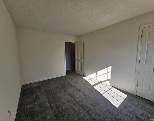 spare room with dark carpet and a textured ceiling