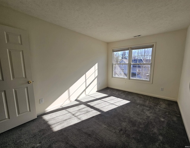 spare room featuring a textured ceiling and dark colored carpet