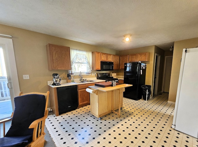 kitchen featuring sink, black appliances, a textured ceiling, and a kitchen island