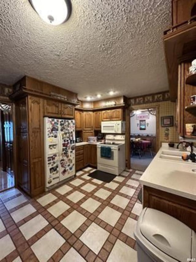 kitchen featuring sink, a textured ceiling, and white appliances