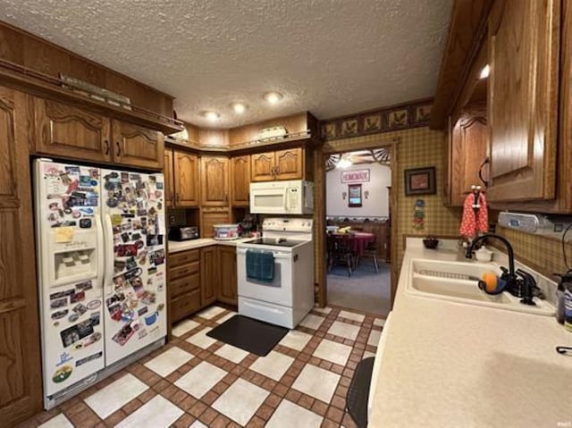 kitchen featuring sink, a textured ceiling, and white appliances