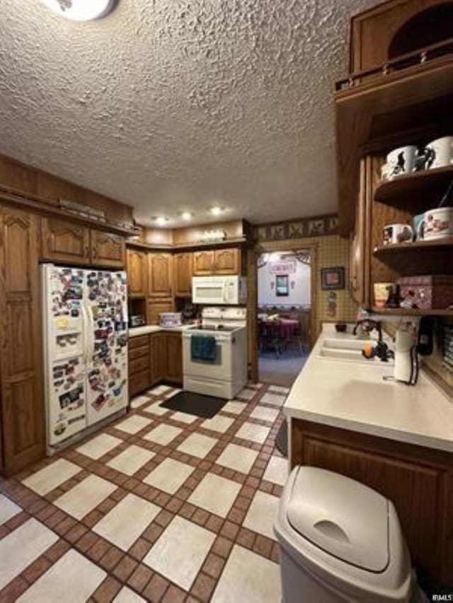 kitchen with sink, white appliances, and a textured ceiling