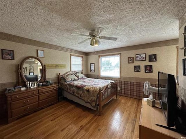 bedroom featuring ceiling fan, hardwood / wood-style floors, and a textured ceiling