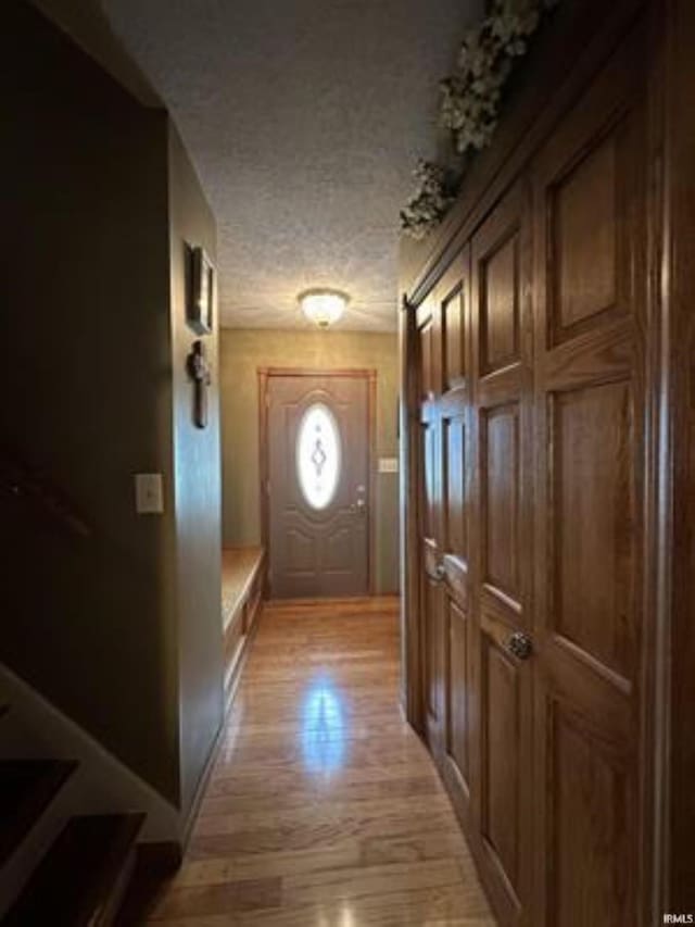 doorway to outside with a textured ceiling and light wood-type flooring