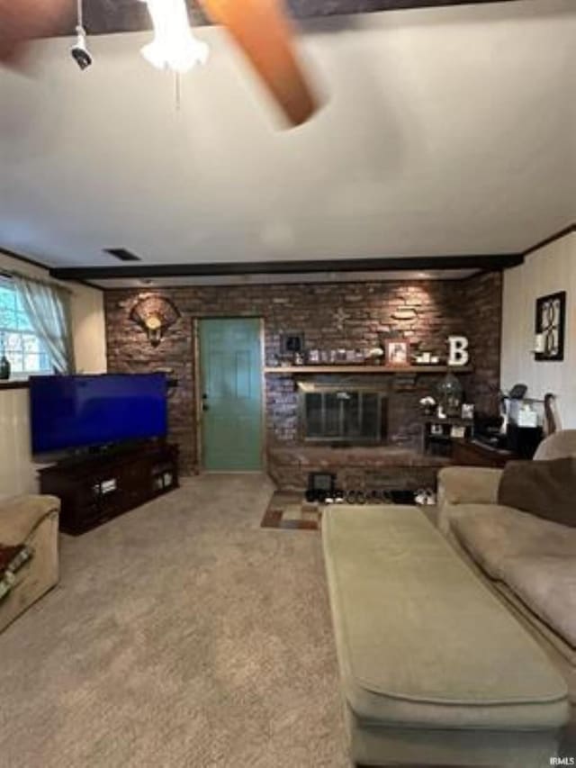 carpeted living room featuring a brick fireplace and ceiling fan