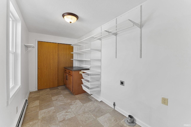 laundry area with a baseboard radiator, hookup for an electric dryer, and a textured ceiling