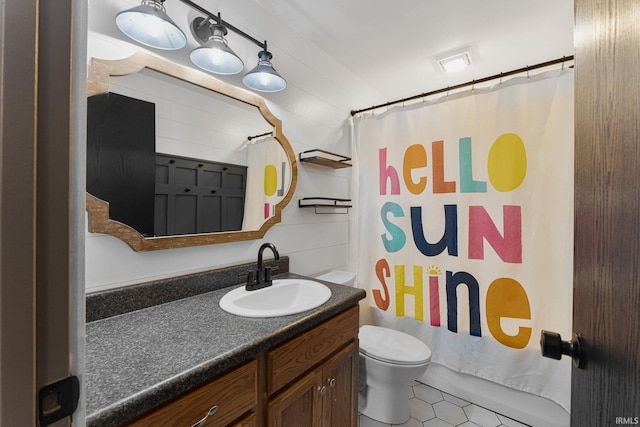 bathroom with tile patterned flooring, vanity, walk in shower, and toilet