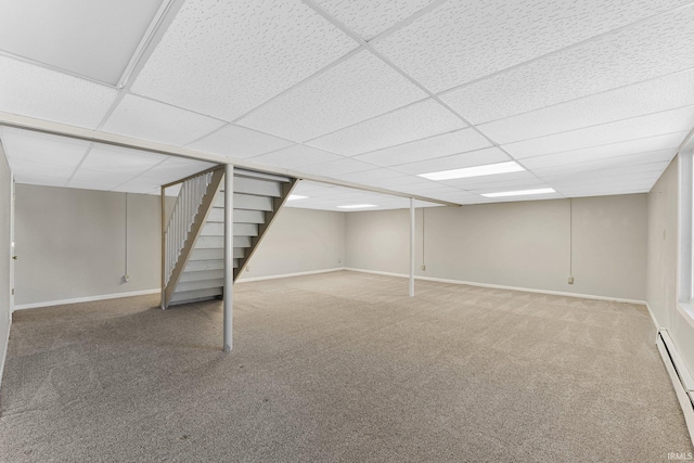 basement with carpet, a baseboard heating unit, and a paneled ceiling