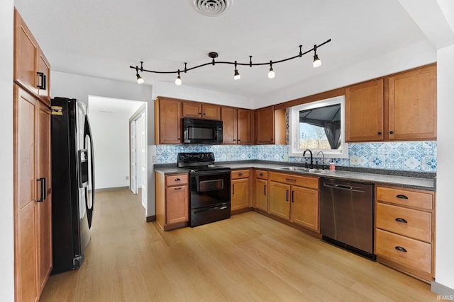 kitchen featuring backsplash, sink, light hardwood / wood-style flooring, and black appliances