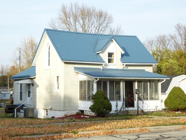 view of front of house with central AC unit and a sunroom